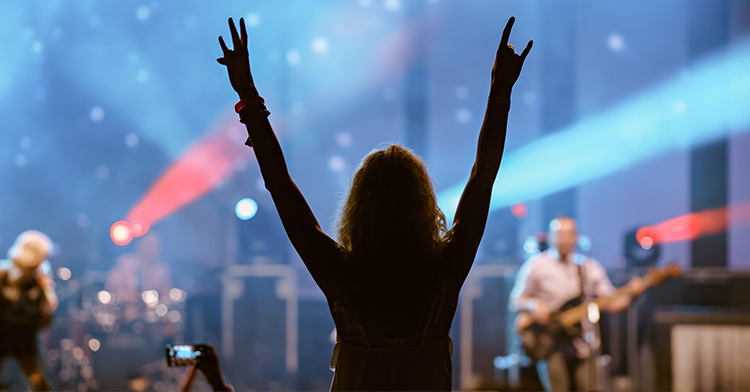 silhouette of kid holding both arms up at a concert