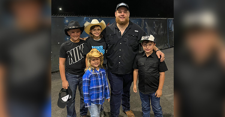 luke combs smiling as he poses with bo tanner, and two other kids.