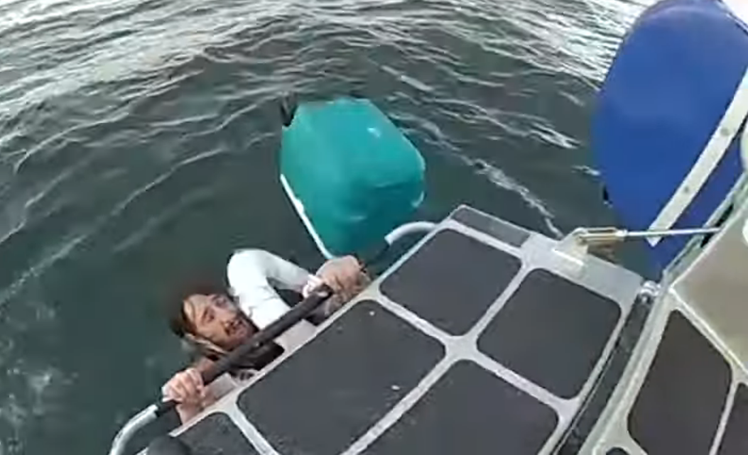 tommy azeredo clings to rescue boat after his vessel sank in the boston harbor.
