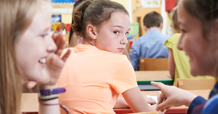 girl looking back uncertainly at other two girls who are giggling