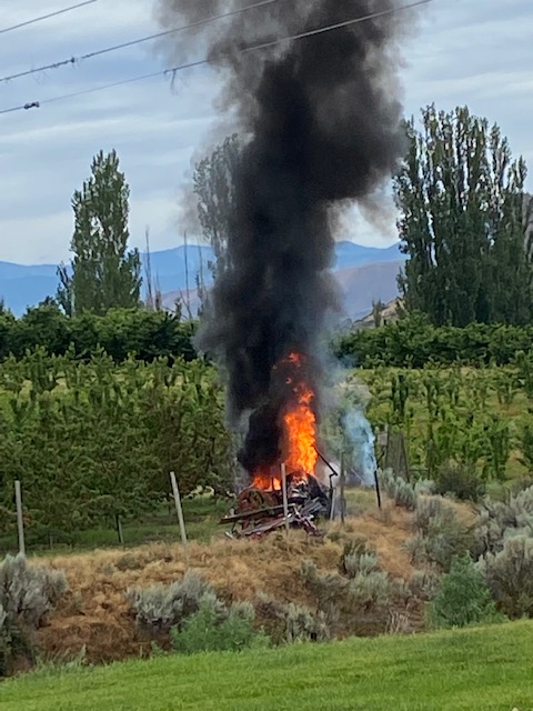 tractor and helicopter on fire in cherry orchard in Wenatchee, Washington.