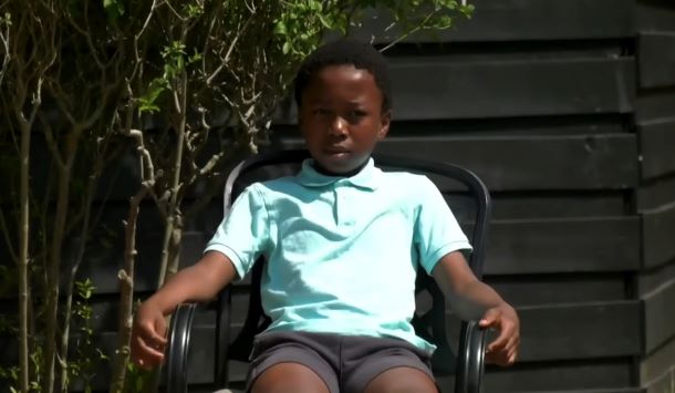 Young David sitting in a chair outside.