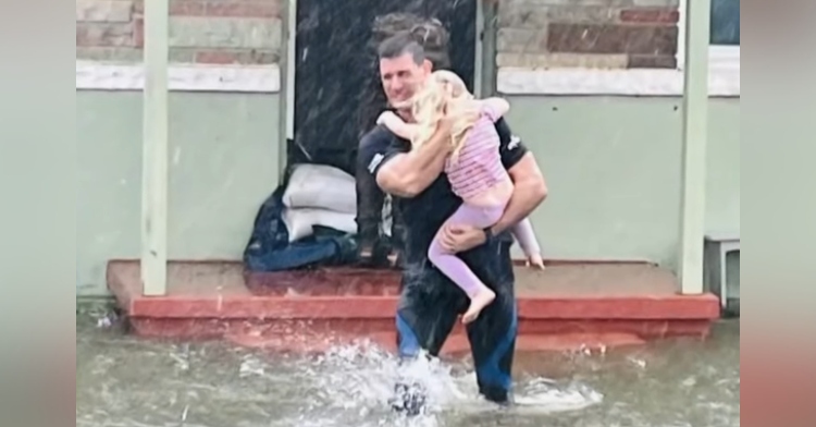 Firefighter Hardus Oberholzer carries small child from flooded home during Hurricane Ian