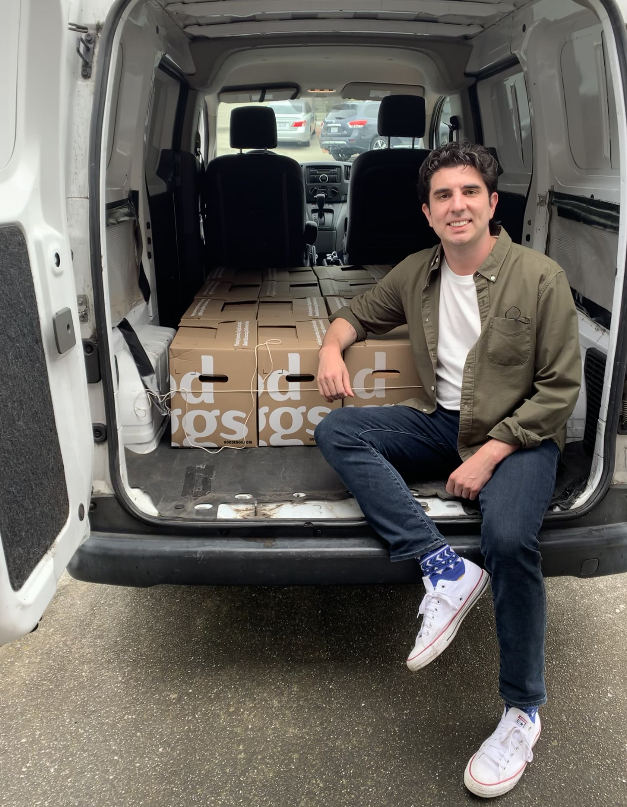 bryan tsiliacos posing inside a van full of boxes ready for delivery