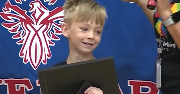 third grader Garrett Brown smiles while being awarded hero certificate
