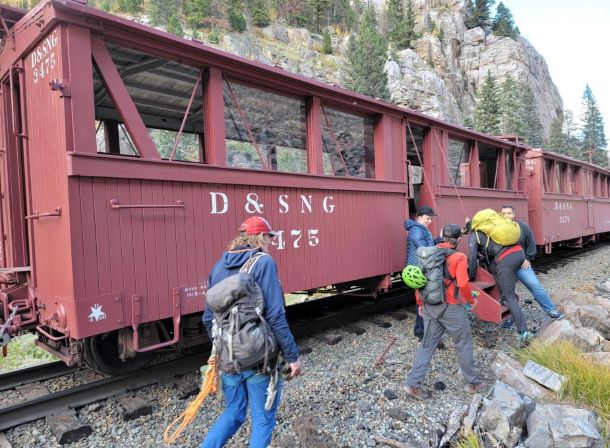 Four hikers standing near a train.
