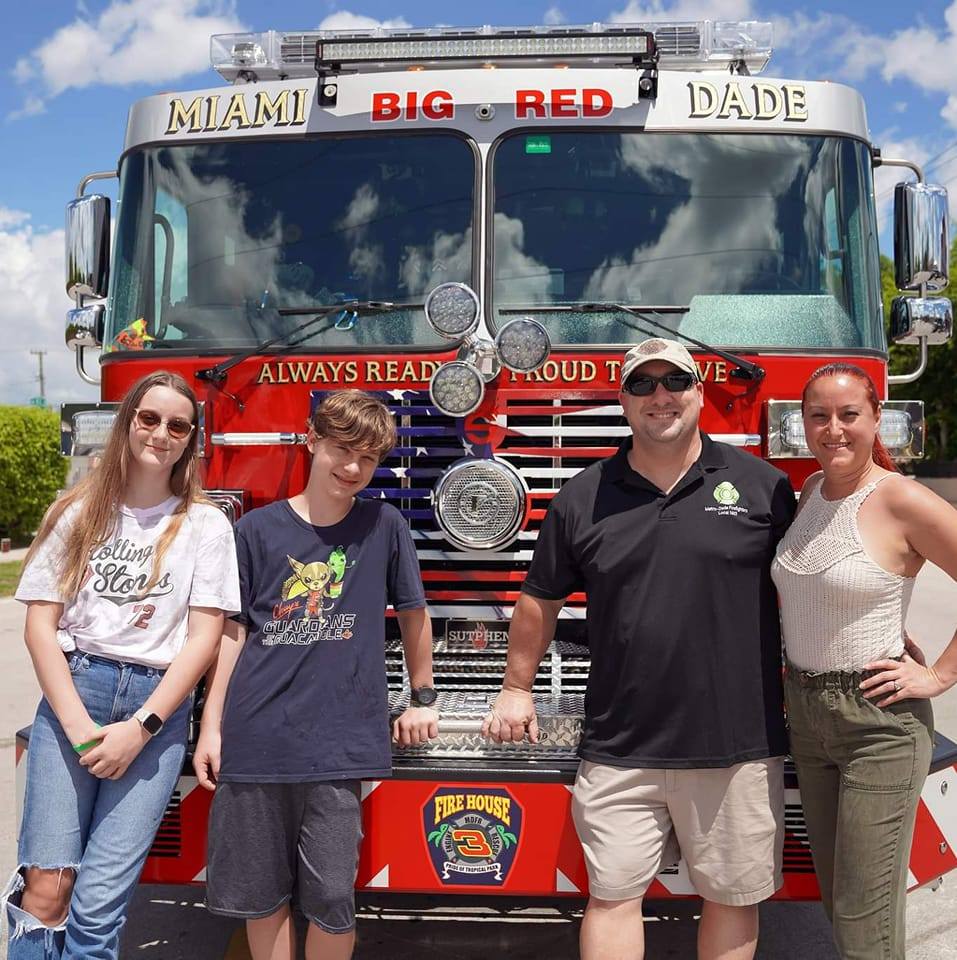 Jeff Hackman and his family standing in front of a fire truck.