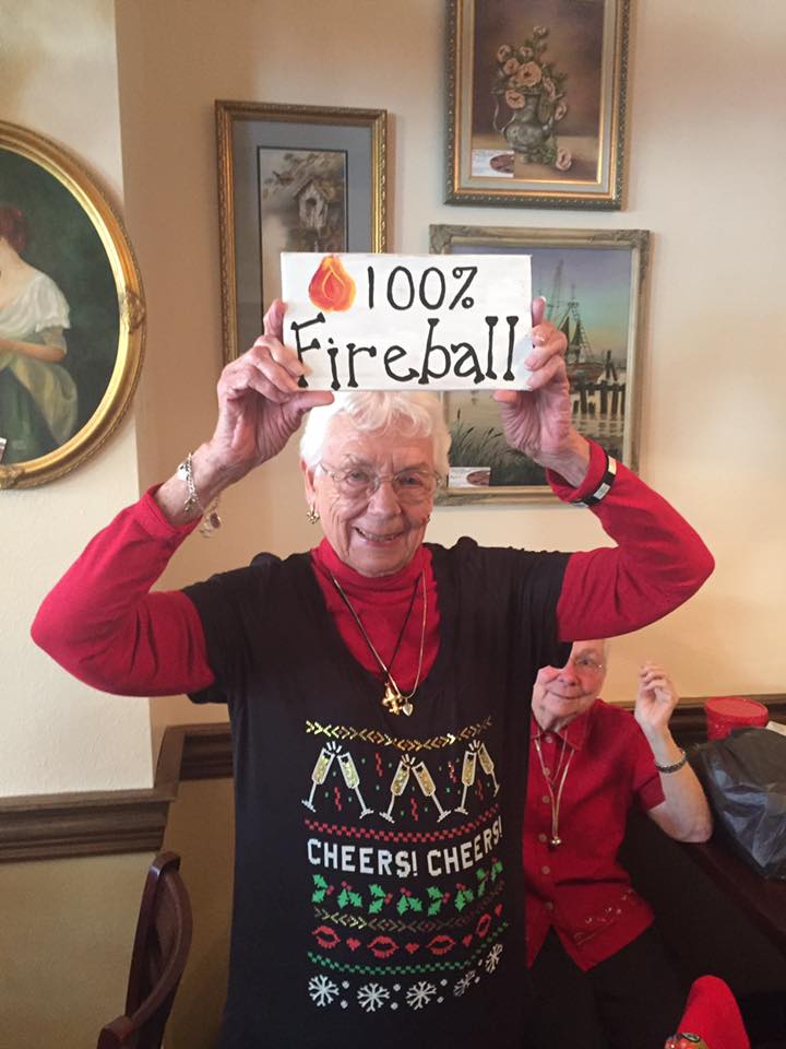 Margaret Masters smiling as she holds up a sign that says "100% fireball."