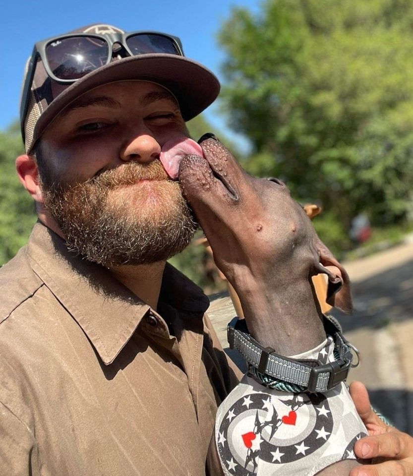 UPS man gets a kiss on face from dog.