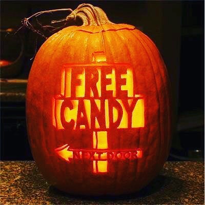 pumpkin carved with words "free candy next door" and an arrow.