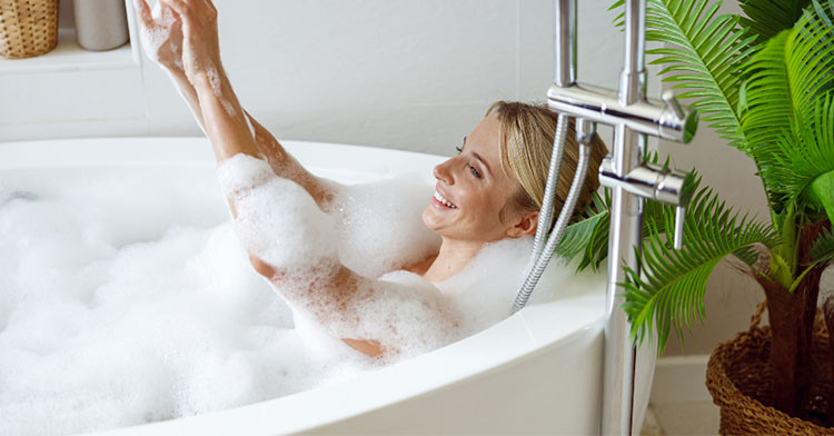 woman taking a bubble bath and smiling