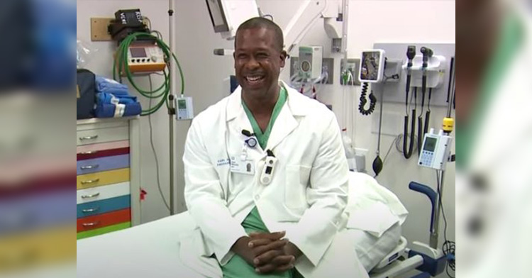 Carl sitting in hospital room on a bed and smiling.