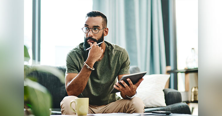 man holding a tablet and pencil and looking contemplative