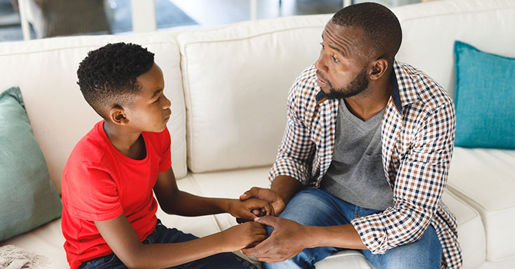 father and son sitting on the couch and holding hands