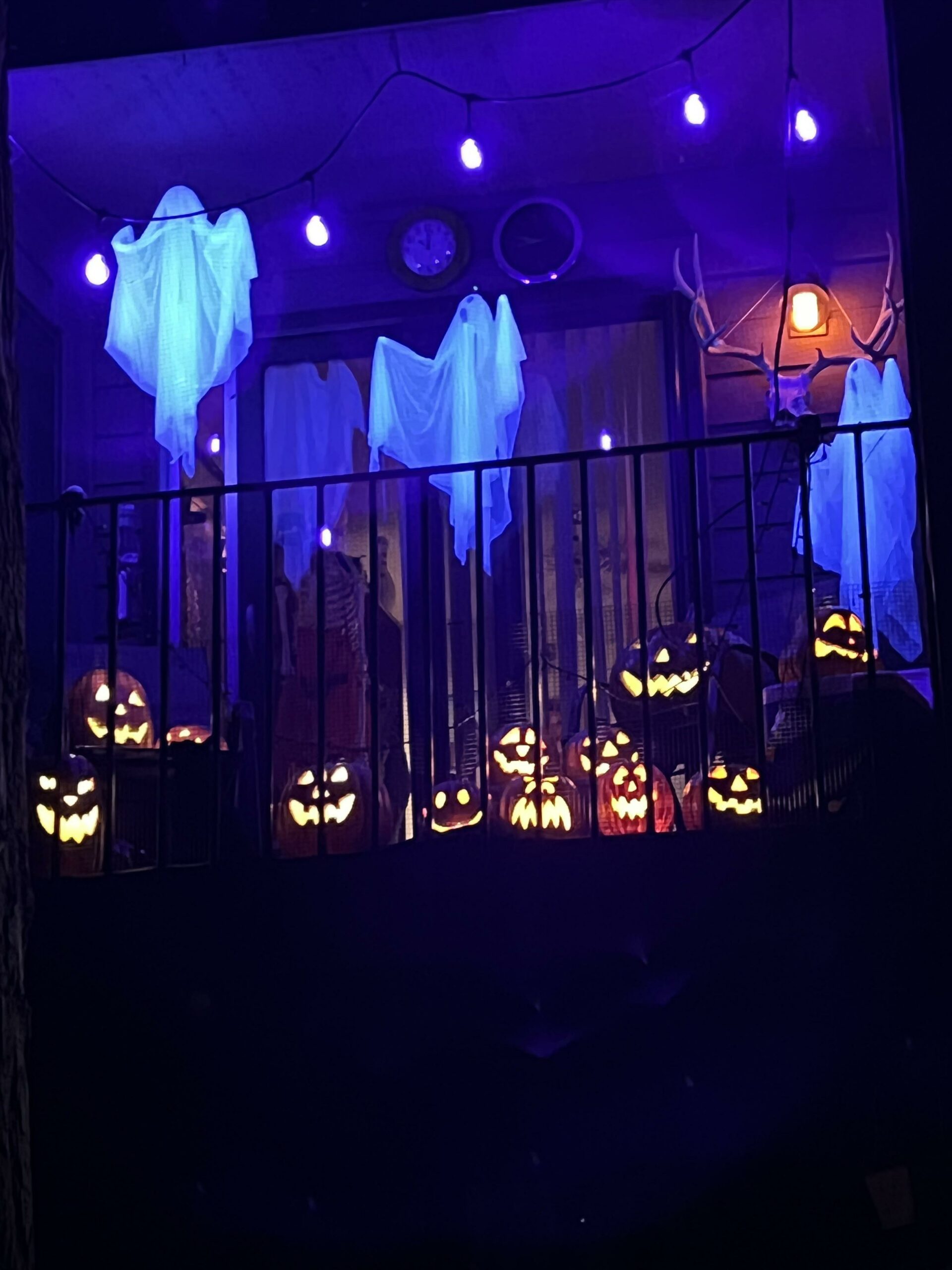 apartment balcony decorated for Halloween with glowing ghosts.