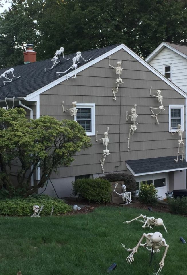 fake skeletons climbing all over house for Halloween