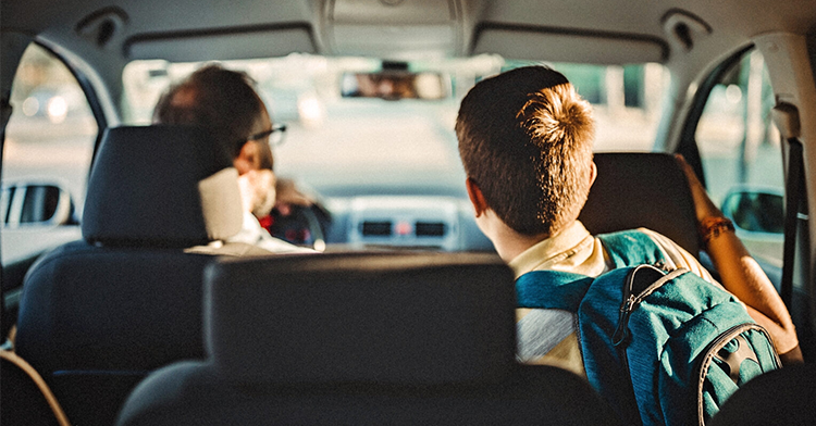 picture of boy in the backseat of the car looking at his dad in the front seat