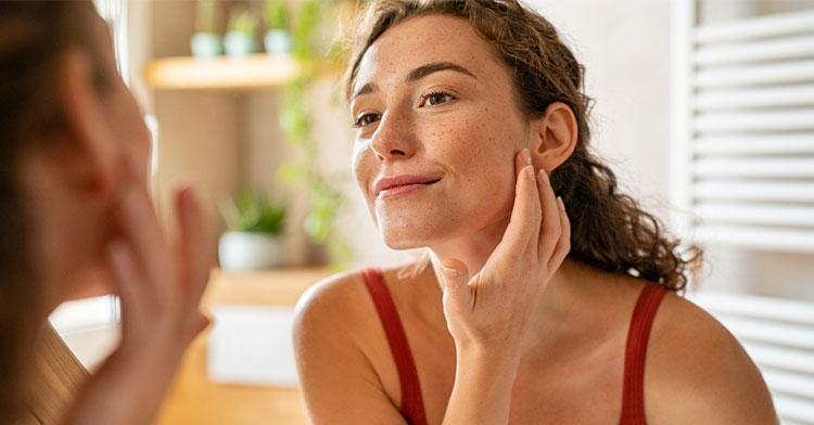 woman examining her face in a mirror