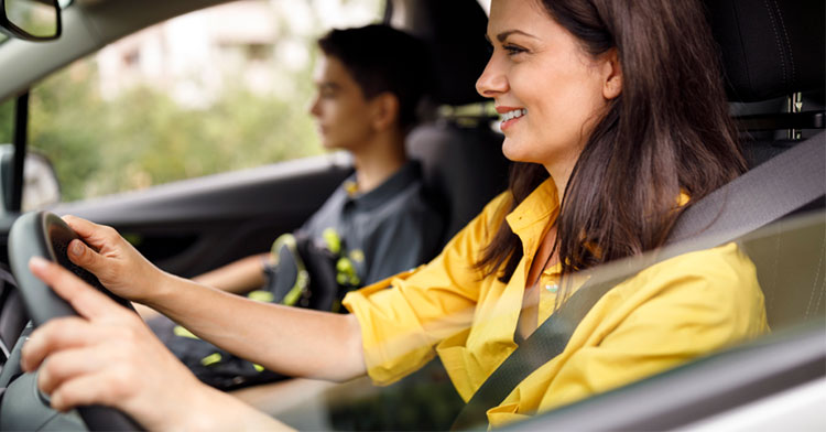 mom driving in car with teenage son sitting beside her