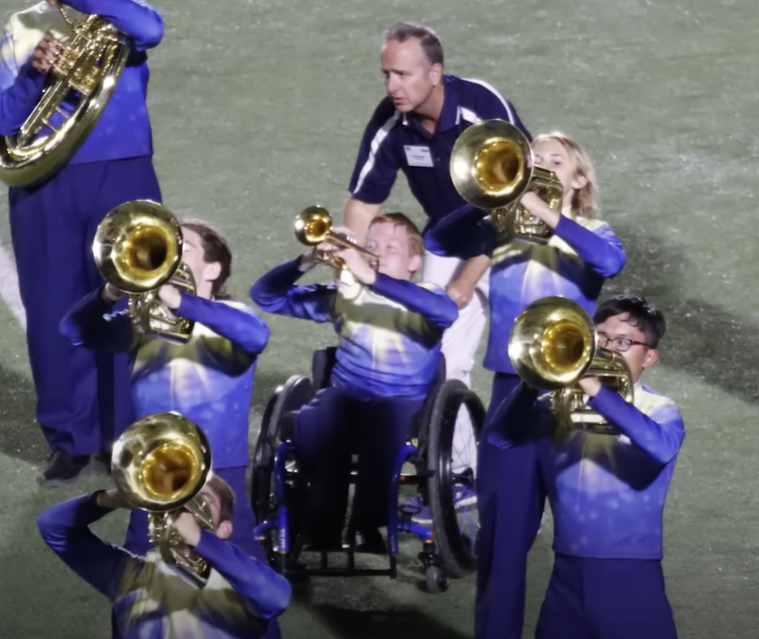 Adam Mewhorter pushes Casey Hubbard's wheelchair in marching band performance.