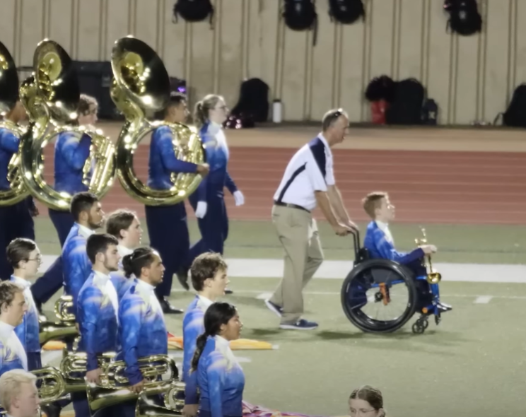 Adam Mewhorter pushes Casey Hubbard's wheelchair in marching band performance.