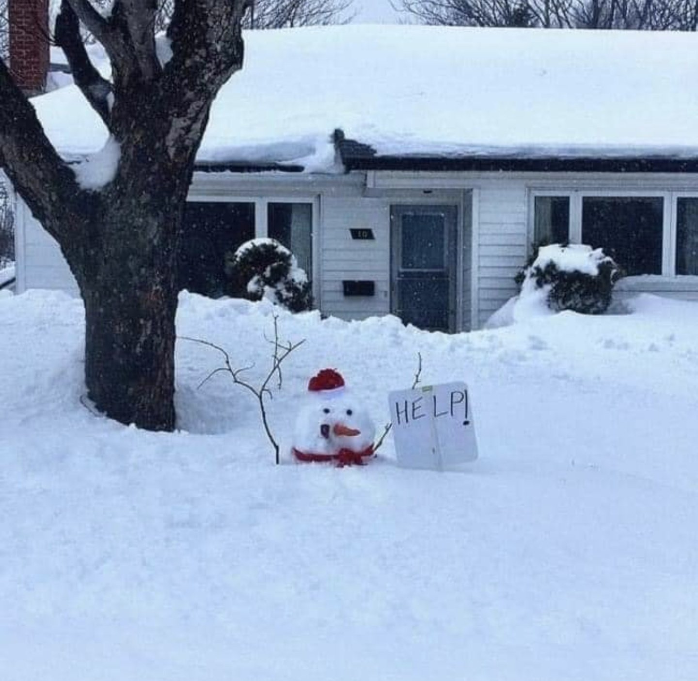 Snowman holding up a sign that says "help" as he drowns in deep snow.