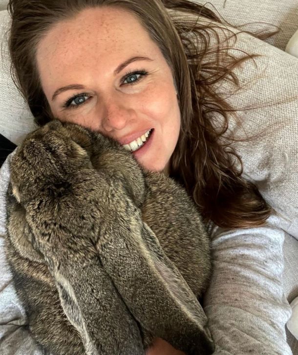 Danielle cuddling with her bunny named Guus resting on top of her as she takes a selfie of them.