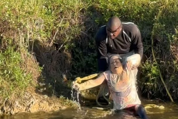 A man is helping pull a woman out of the water.