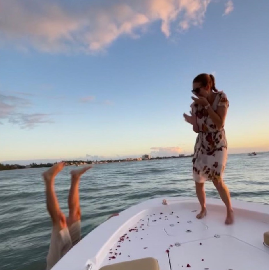 Suzie Tucker laughs in shock as boyfriend Scott Clyne dives into ocean after dropped engagement ring.