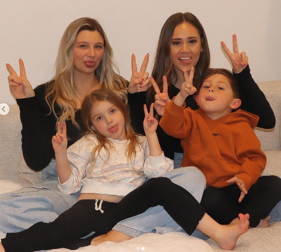 Lauren and Samantha Pose with Their Children, Haidyn and Kaelin. The Kids are Seated on Their Mother's Laps, and Everyone is Making the Peace sign With Tongues Sticking Out.