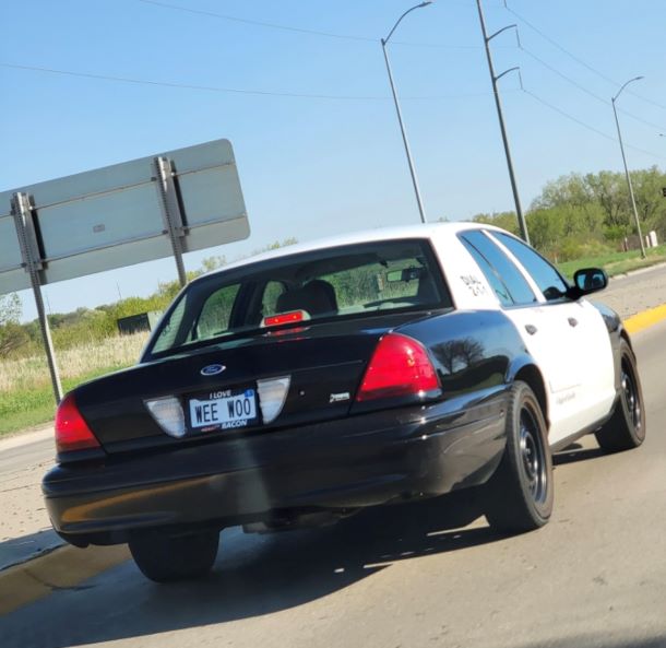 A retired police car with a license plate that spells out the sound the siren makes.