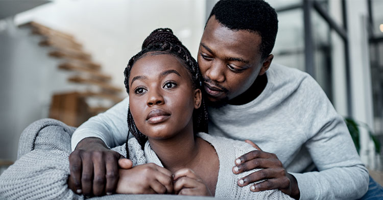 man putting his hands on woman's shoulders from behind