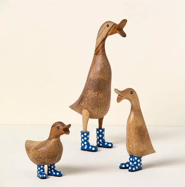 trio of wooden duck sculptures wearing polka dot rain boots