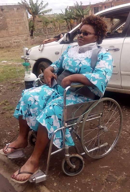 Gladys sitting in a wheelchair outside with a neck brace on and an oxygen tank at her side.