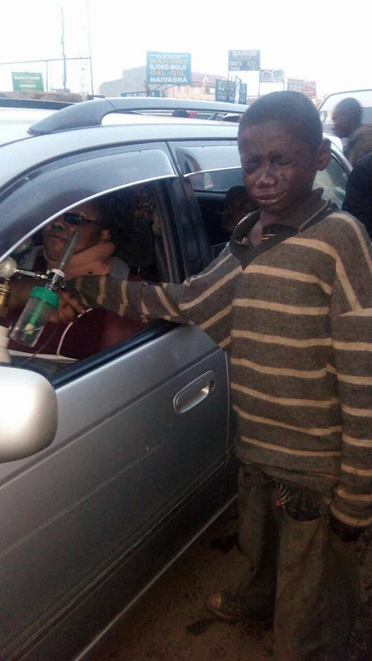 John is in tears with his eyes closed as he holds Gladys' hand who is sitting in a car.
