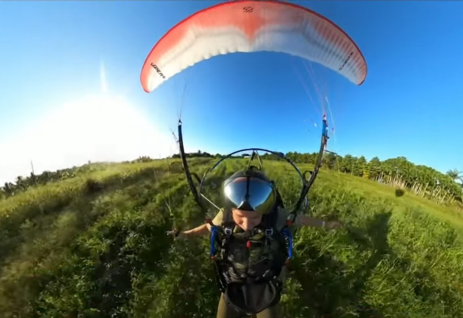 Front-facing view of Cristiano paragliding to the ground.