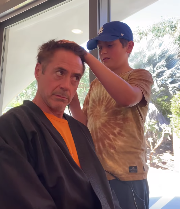 robert downey jr. getting his head shaved by one of his sons. 