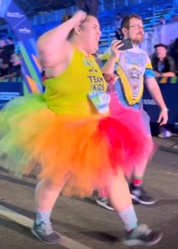 A woman dressed in a rainbow tutu finishes a marathon.