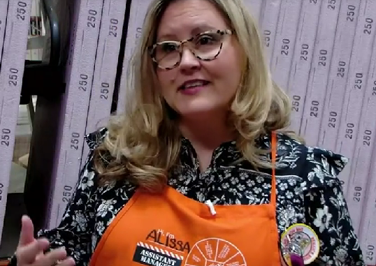 Assistant Manager, Alissa Rocchi, Faces the Camera and Smiles. She is Wearing an Orange Home Depot Apron.