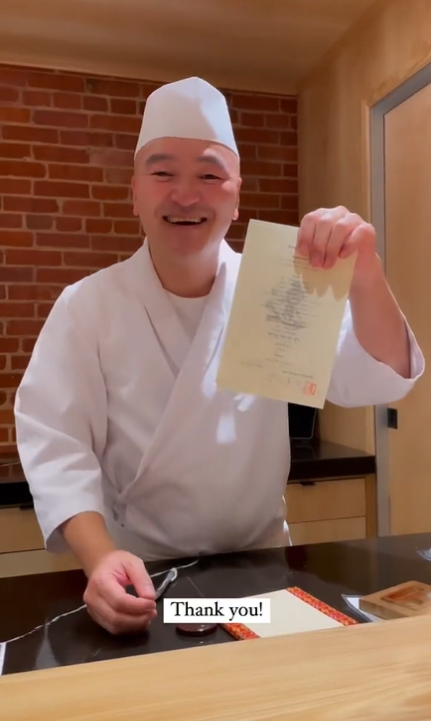 Chef Tatsuya Sekiguchi holding up menu at Tatsu Dallas.