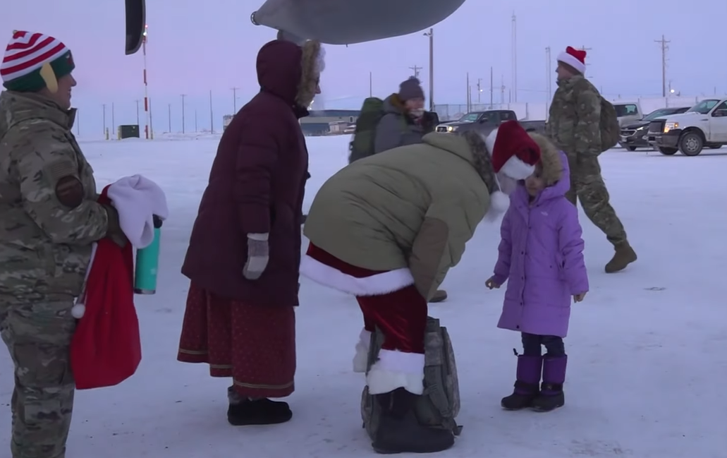 Santa Claus kneels to talk to an excited child in Nuiqsut, Alaska.