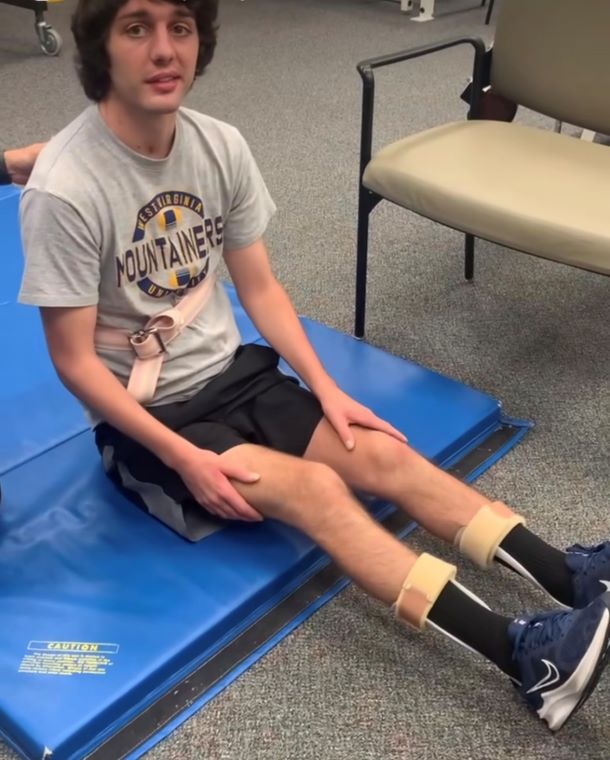 Cody sits on a mat during a physical therapy session.
