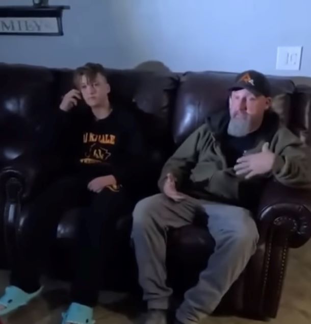 A father and is teenage son are sitting on a couch.