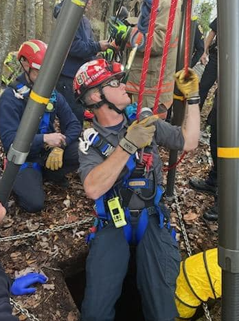 A Male First Responder is Attached to a Pulley and Being Lowered into a Well.