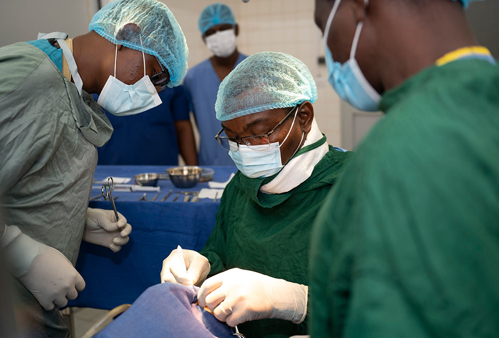 Dr. Grégoire Akakpo-Numado performing cleft surgery while two other medical professionals help.
