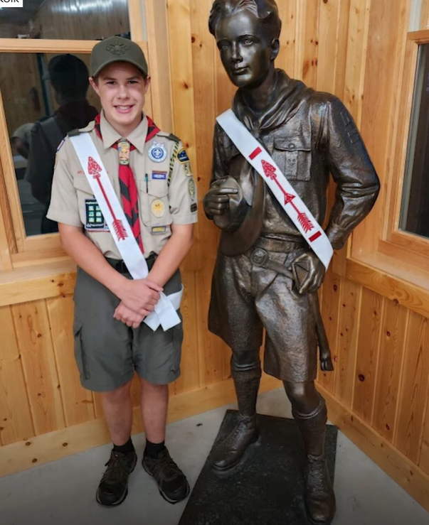 Jonathan Werner wears his Boy Scouts uniform and poses with a statue.