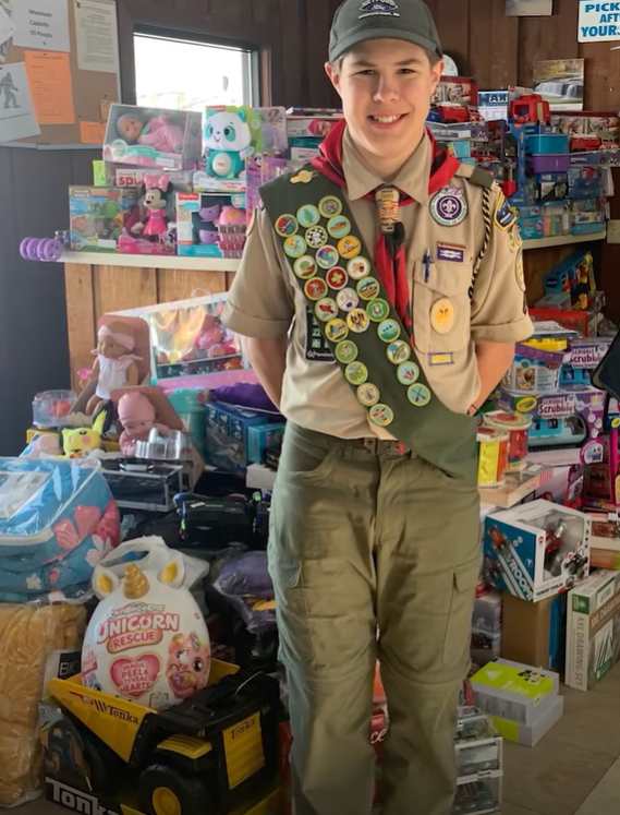 Jonathan Werner wears his Boy Scouts uniform and poses with gifts he purchased for other kids.