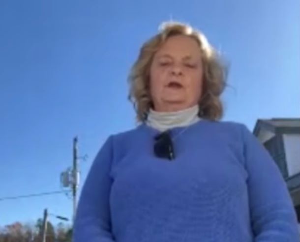 A woman wearing a blue sweater is speaking.