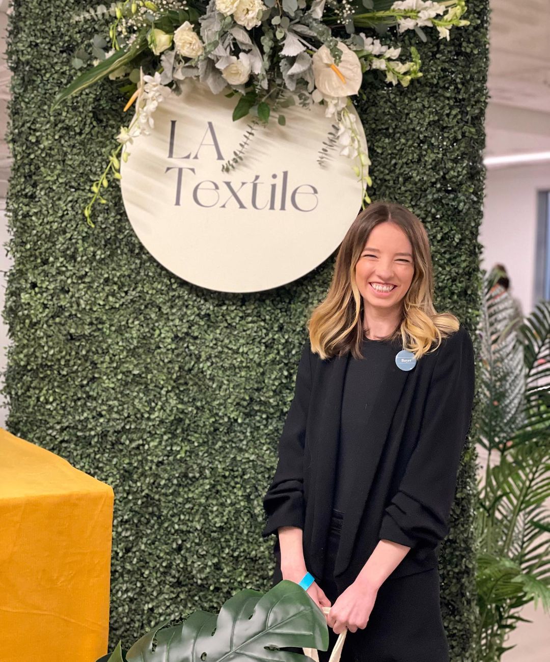 Fashion designer Lovell Faye smiling in front of a sign that says LA Textile.