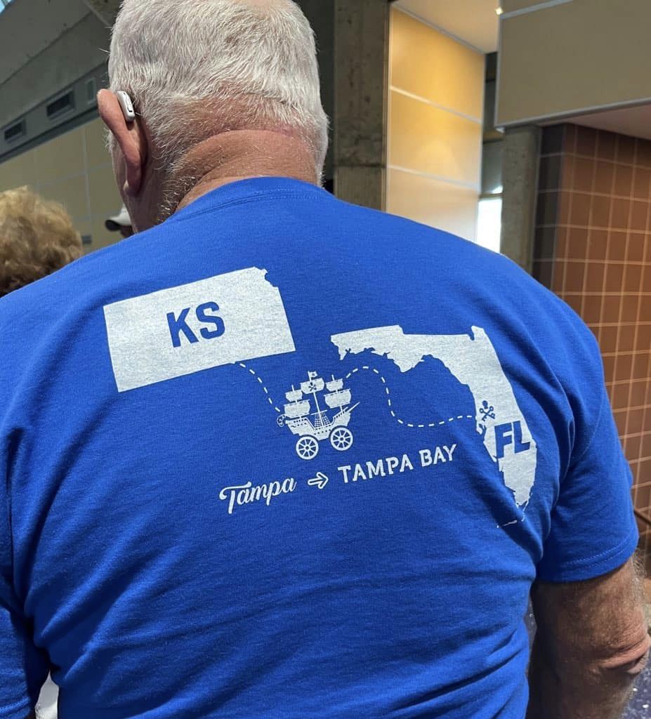 man showing the back of his t-shirt that shows a map between Tampa, Kansas to Tampa, Florida
